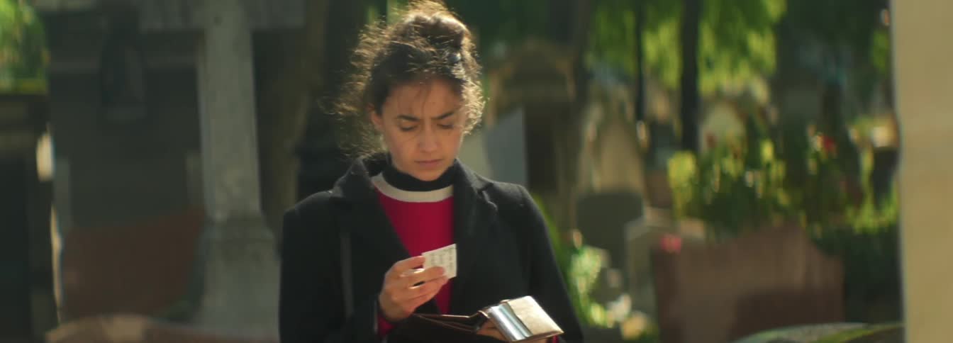 An indian woman looks over a card from her wallet