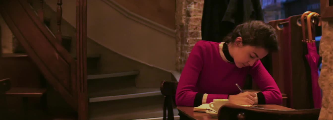 Woman sits at table and writes down at home by night