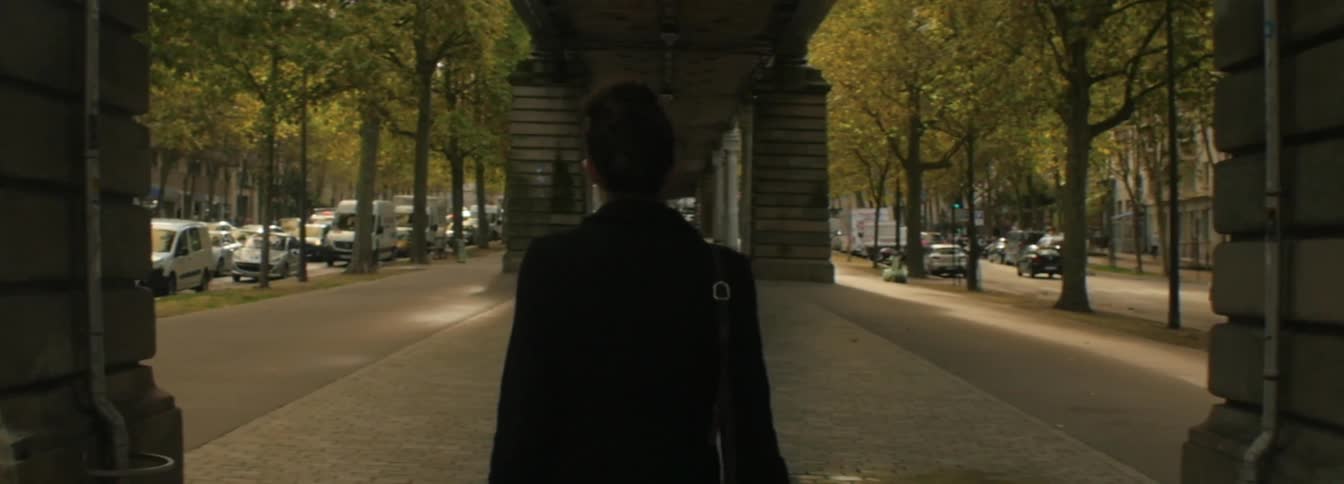 Woman walks under a long old overpass between two city streets