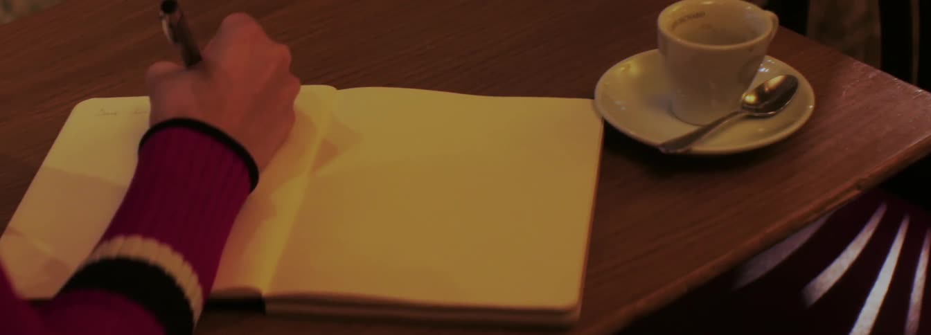 Someone writes in a notebook with a pen