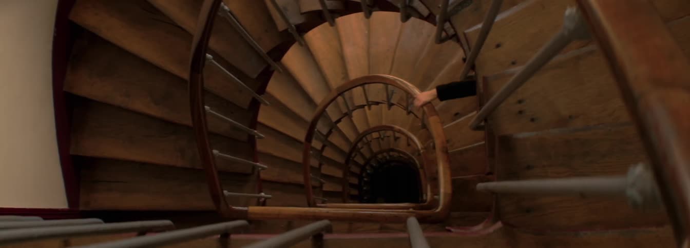 Person wearing suit descends down the spiral stairs