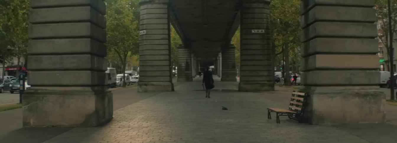 A person walks under a huge bridge between two city streets