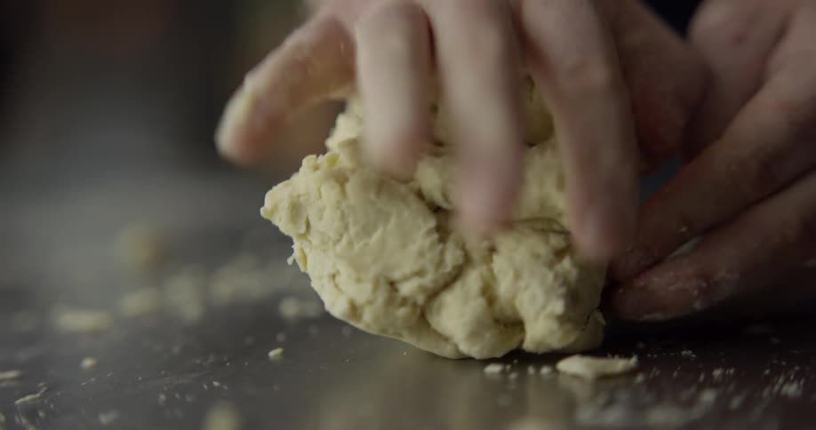 Man kneads yellow dough indoors
