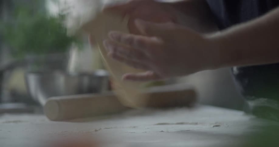 Man spreads the dough in the kitchen in the daytime