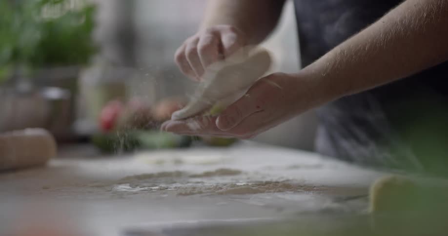 Dough being powdered and flipped by a man