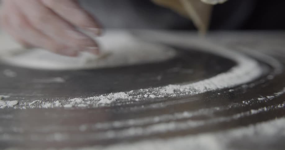 Mans hands working dough and laying it on a table