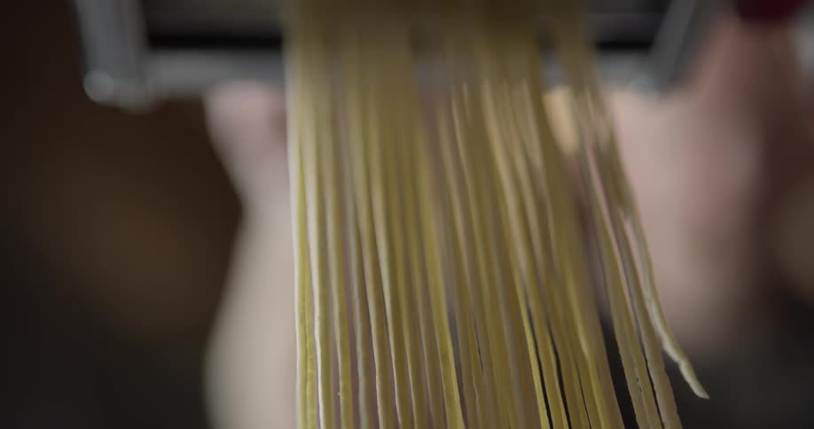 Spaghetti coming out of a pasta roller