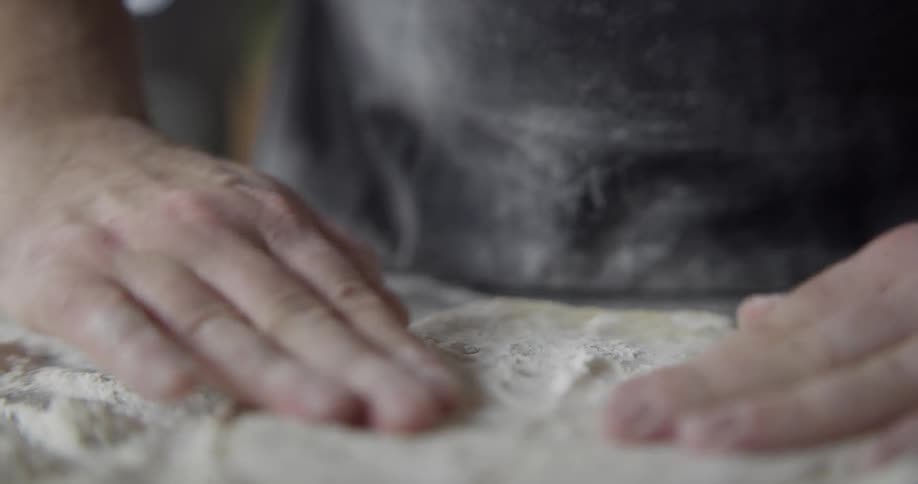 A man is preparing dough indoors