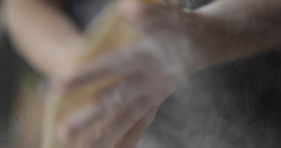A chef with flour dusted hands works a piece of dough