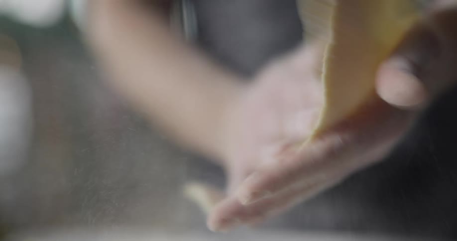 A man slaps a piece of dough between his hands