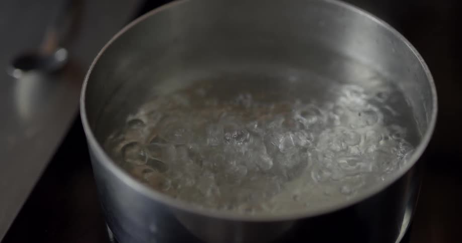Mans hand taking a lid off a pot of boiling water