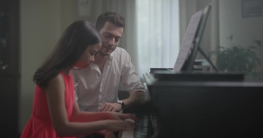 A man teaches a girl piano