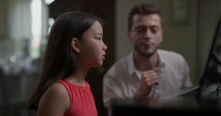 A man teaches a girl how to read music
