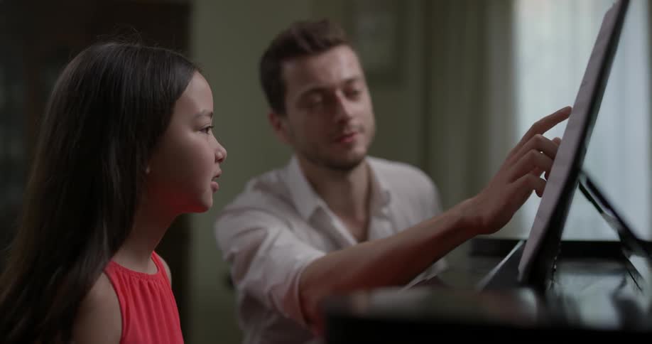 A young girls music teacher goes over the music to play