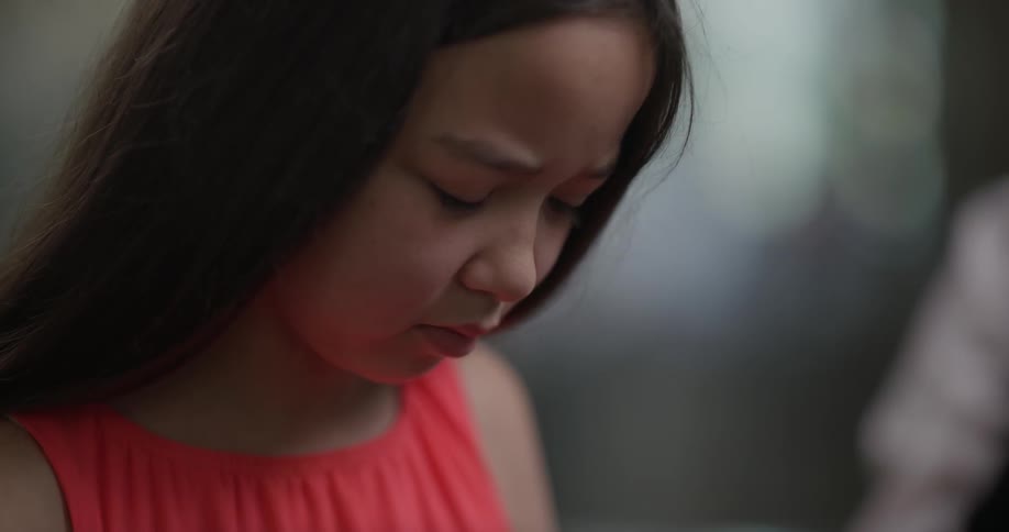 A young girl frowning while looking down at something off camera