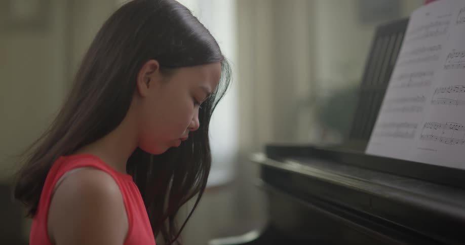 Little girl plays the piano indoors in the daytime
