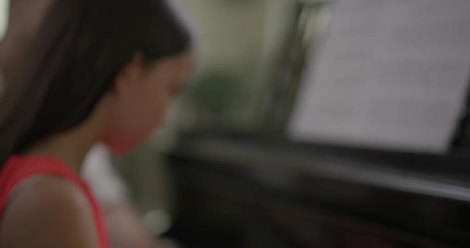 Young asian girls plays on a piano with a teacher