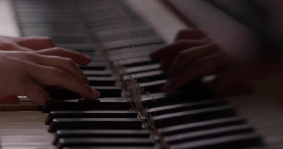 A pair of strong hands strokes the keys of a piano