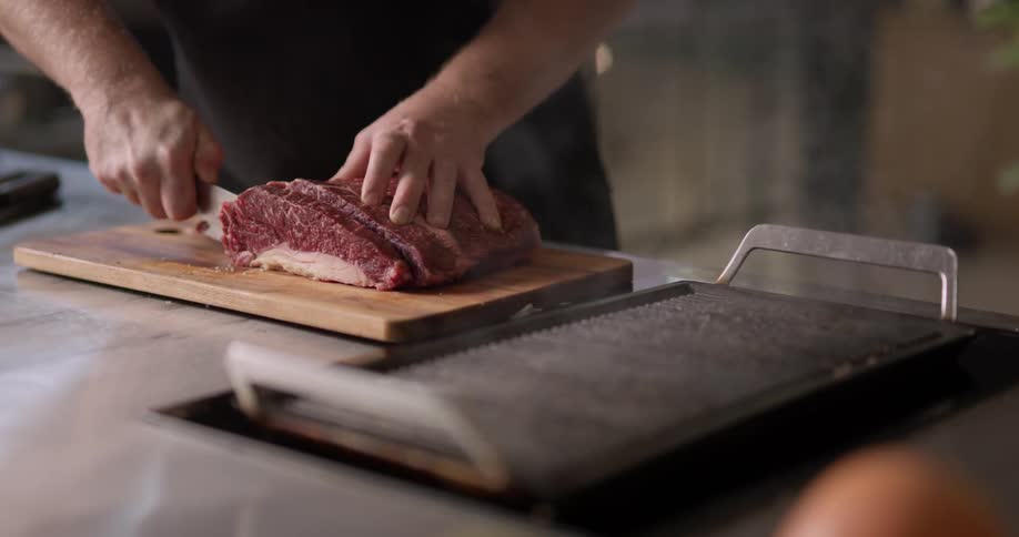 Mans hands slicing meat on a cutting board