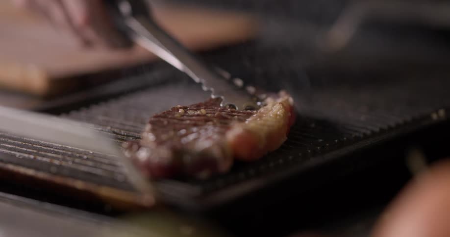 A steak is flipped on a griddle