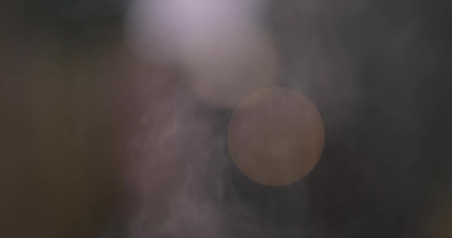 Smoke rises up and light glares in circles