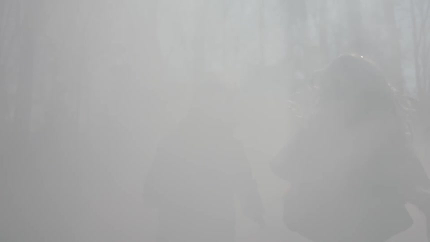 A girl and boy run in foggy woods