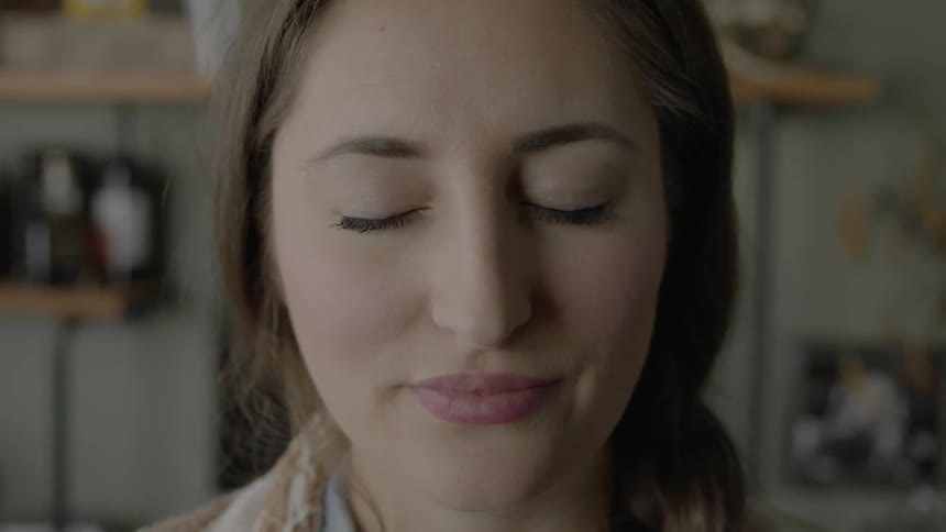 A woman stands with her eyes closed
