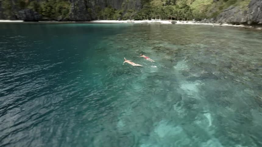 Two people swimming in a large body of water on a sunny day