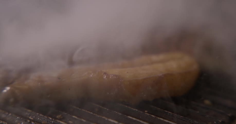 Vegetables are cooking on a grill with a cloud of steam coming from them