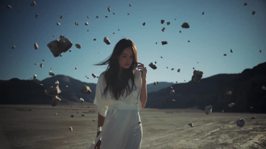 Rocks fly off the ground around a woman in the desert