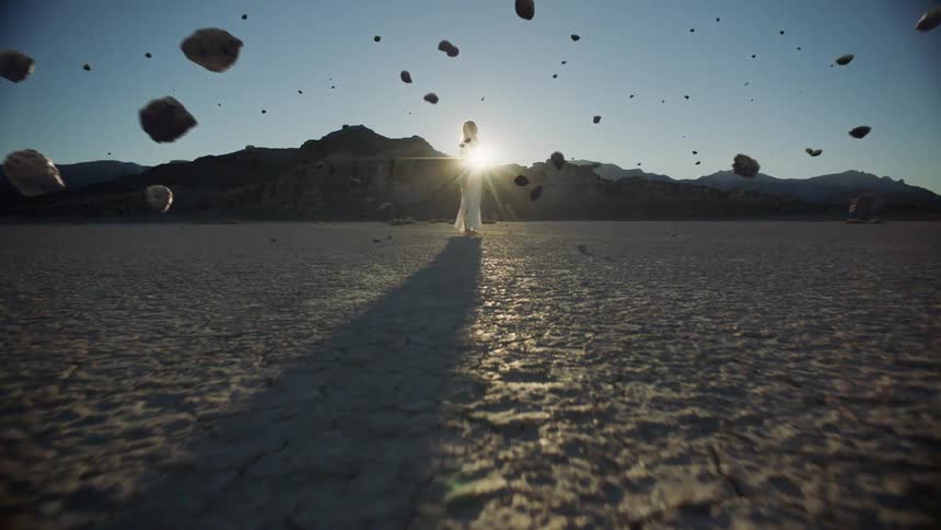 Rocks float around a woman in the desert