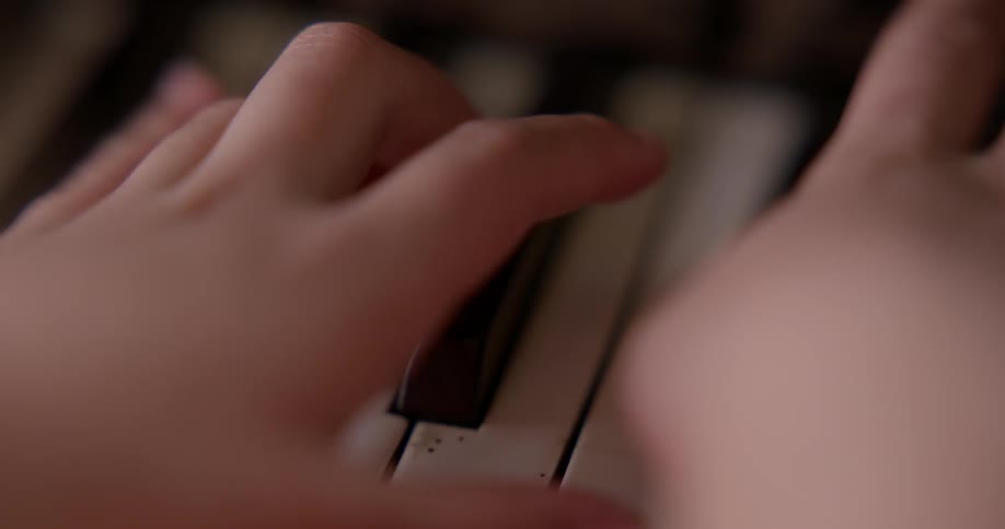 Childs hands playing on the piano close up view