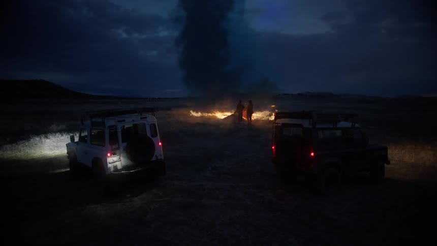 Two people are standing in front of the huge fire