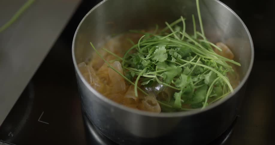 A chef adds some parsley to a stew and mixes it in with a spoon