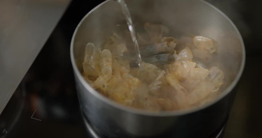 Liquid is being poured in a pot with shrimp
