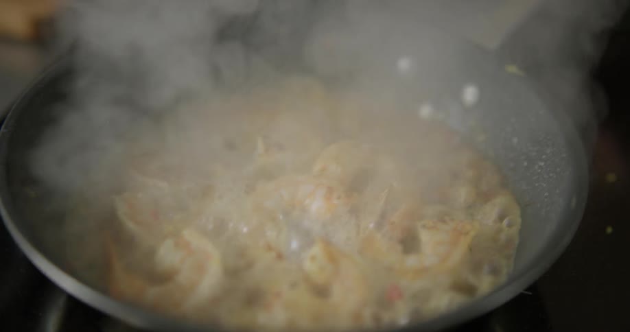 A person pours liquid into a frying pan and shakes it