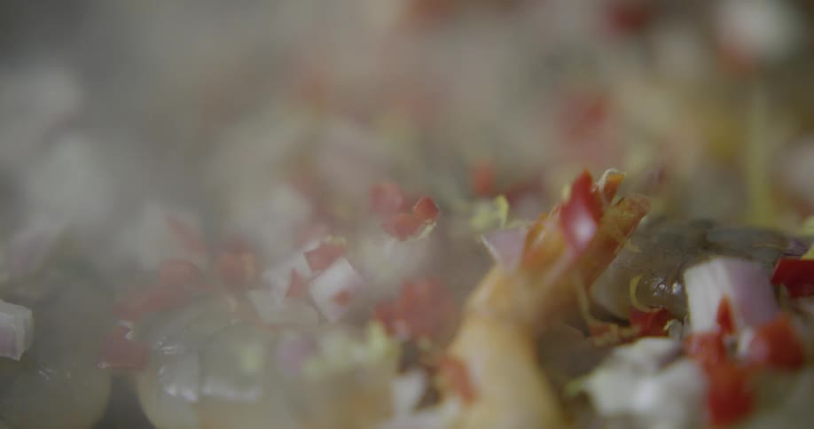 Spices are added to shrimp and onion being grilled