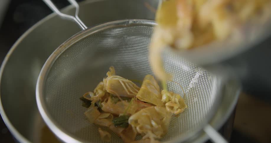 A person spoons ingredients into a sieve