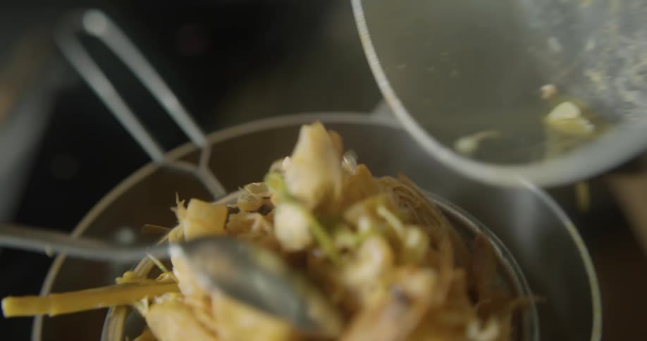 A mixture of cooked vegetables and past are poured into a strainer over a metal pot and then compressed with a spoon to remove excess liquid