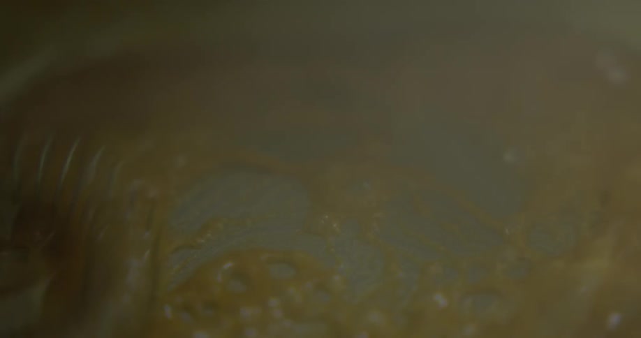 A person whisks melting butter in a pan