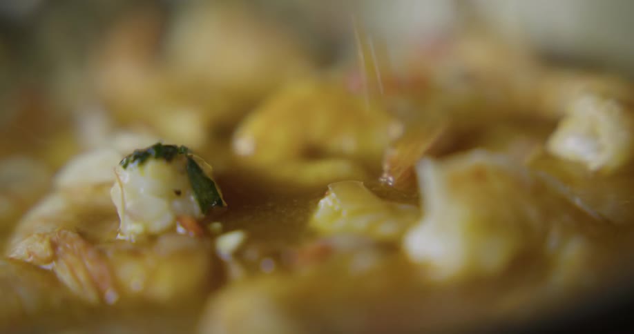Sauce is poured over shrimp cooking in a pan
