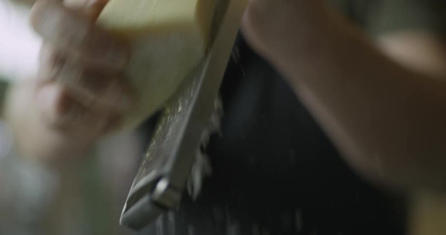 A man grates a block of cheese