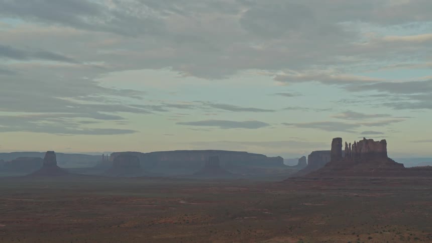 The camera looks out over a vast desert with towers in the distance