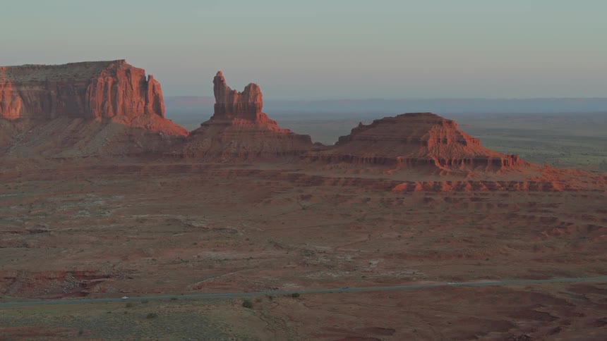 An arid desert landscape at low sun with three protruding hills