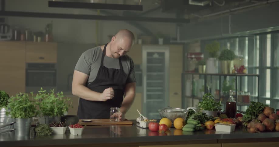 A chef puts ingredients into a jar and shakes them vigorously