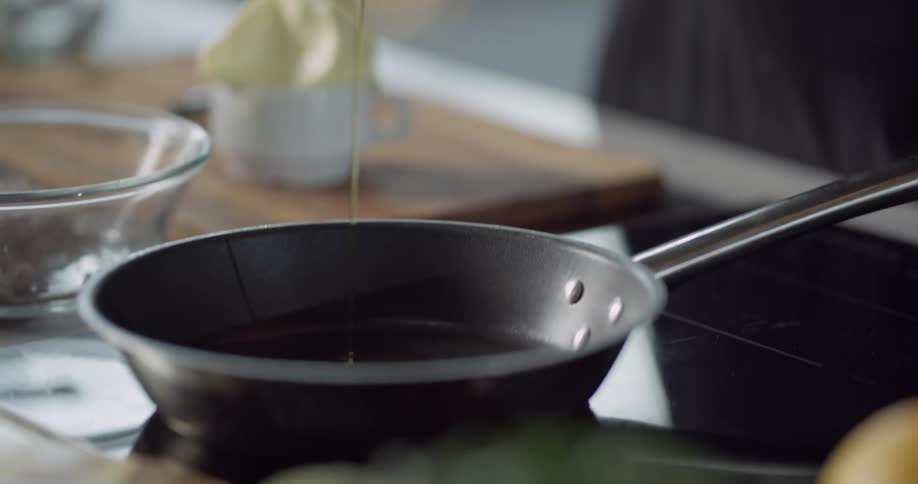 A person pours oil into a pan