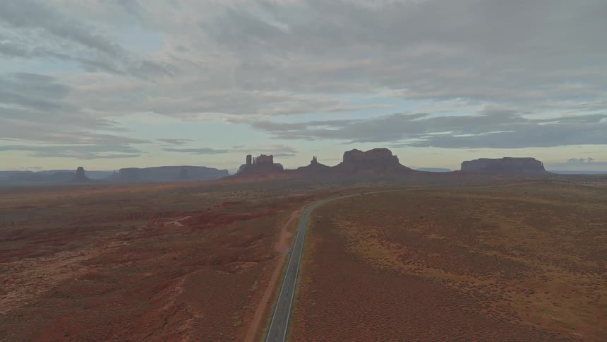 The camera flies over a road going through a desert landscape