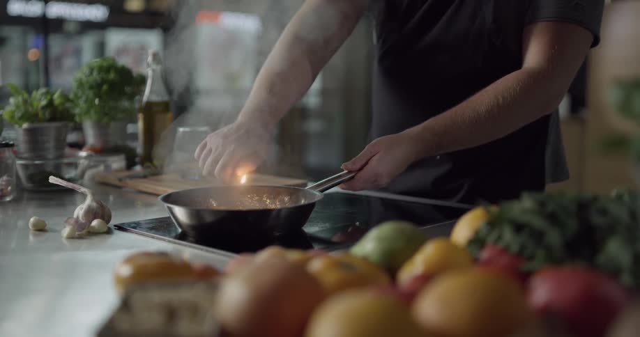 A person pours alcohol into a pan and lights it on fire