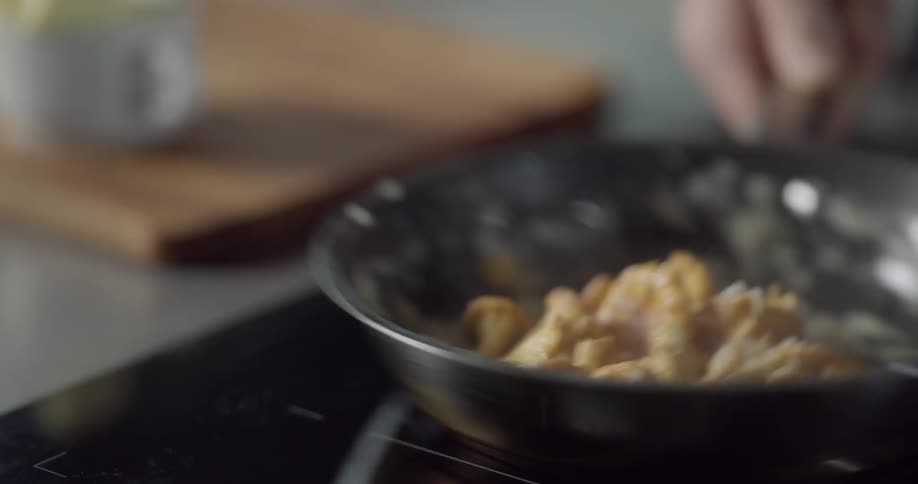 Man adds butter to the cooking food and shakes pan on stove in the kitchen