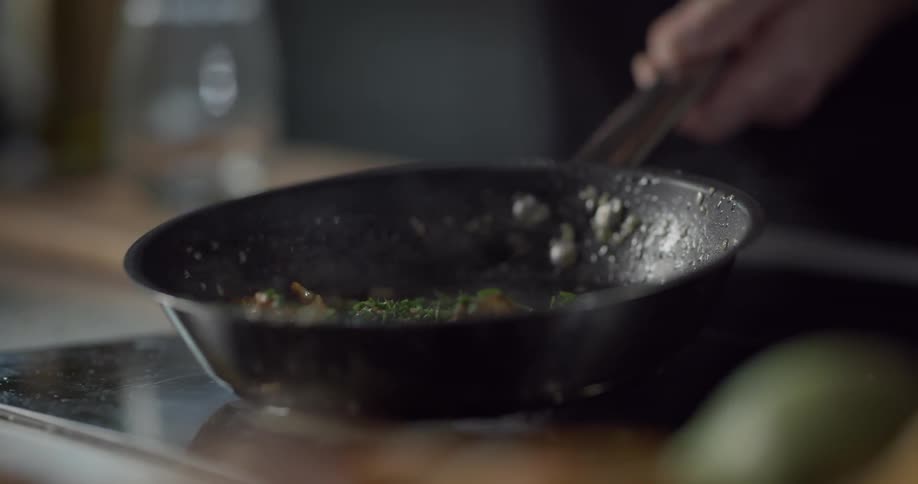 A chef adding items to a saute pan